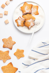 Christmas homemade gingerbread cookie in a plate on a white background, top view, copy space. Freshly baked cookies sprinkled with sugar flat lay. Christmas baking background.