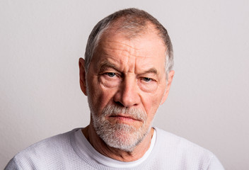 Portrait of a serious senior man in a studio, looking at camera.