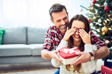 Portrait of man surprising girlfriend with present. Family during Christmas celebration