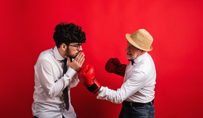Studio shot of young versus old generation, a father and son with boxing glove.