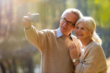 Senior couple taking selfie with smartphone in park