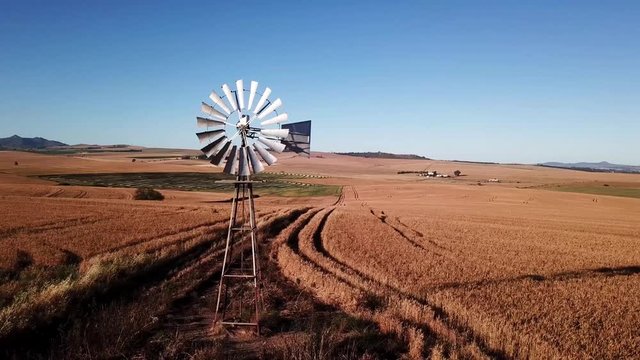 Rotation arial shot of windmill in rural wheat farm land