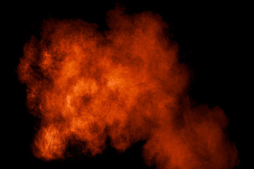 Orange red  powder explosion on black background.Orange red color dust splash clouds.