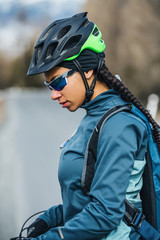 Female mountain biker standing on road outdoors in winter nature.