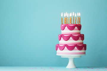 Tiered birthday cake with golden candles - obrazy, fototapety, plakaty