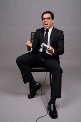 Full body shot of Persian businessman sitting and playing games
