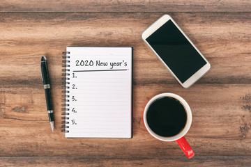 New year Concept - 2020 number and text on notepad. Smartphone, pen and cup of coffee background.