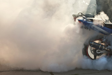 The smoke comes out from under the wheels. Motorcycle wheel closeup. Smoke due to tire rubbing...