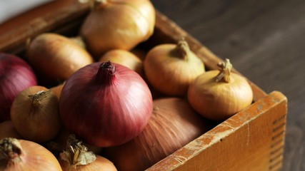 Fresh red and yellow onions in a wooden box