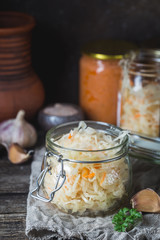 Glass jar with homemade sauerkraut on rustic wooden table