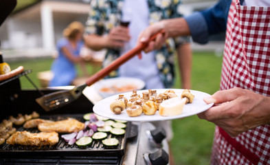 Midsection of family outdoors on garden barbecue, grilling.