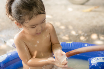 Asian girl kindergarten is having fun playing in the water bath.