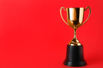 Golden trophy cup on red background. Space for text