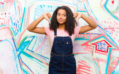young pretty african american woman looking sad, disappointed or angry, showing thumbs down in...