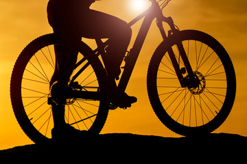 Obraz premium Silhouette of cyclists at bike at sunset. Vehicle closeup. River background.