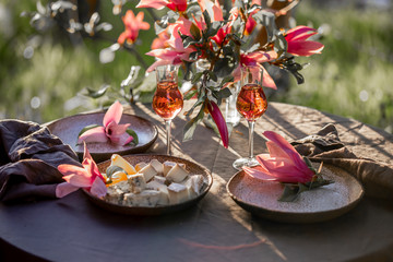 Beautiful table setting in garden on sunset light. Table decorated with magnolia flowers under magnolia tree.