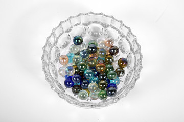 Colored glass bullets in glass bowl on white ground