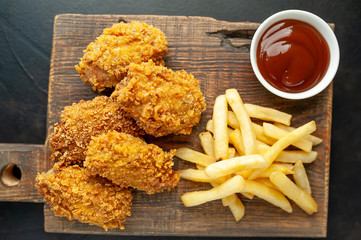 fried chicken with french fries and food nuggets - on stone background