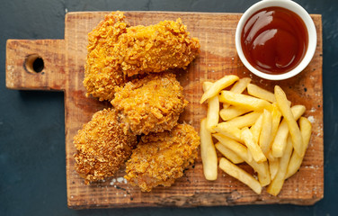fried chicken with french fries and food nuggets - on stone background