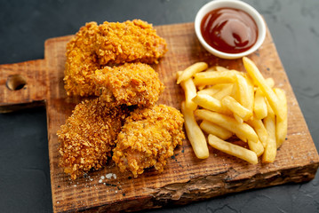 fried chicken with french fries and food nuggets - on stone background