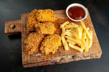 fried chicken with fries and slices of food - on a stone background with copy space for your text
