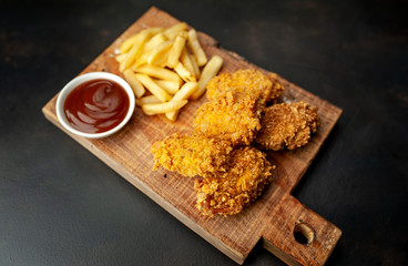 fried chicken with french fries and food nuggets - on stone background