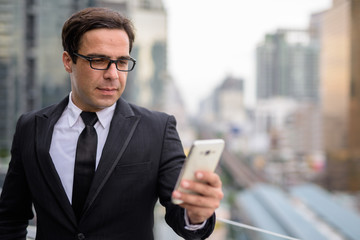 Handsome Persian businessman using phone in the city