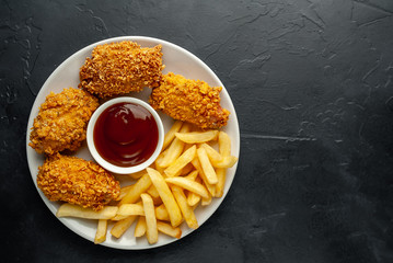 fried chicken with french fries and food nuggets - on stone background