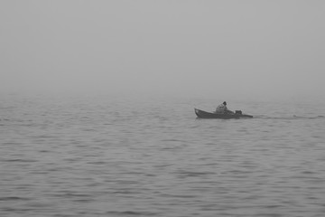 Obraz premium A man floats on an old boat in the fog