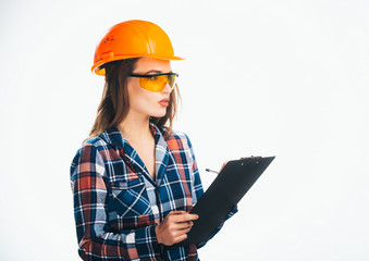 Happy young woman is wearing orange safety helmet and checkered shirt reading clipboard notes. Isoalted background.