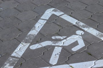 Pedestrian crossing sign in a white triangle on a stone tile in the street. A symbol of caution for populations including students and schoolchildren
