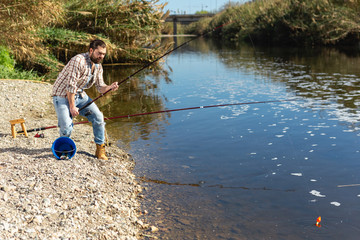 Fototapeta na wymiar Happy fisherman pulls fish out of the river