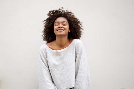 smiling african american woman with curly hair against white wall