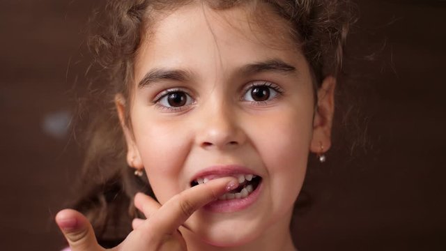 The girl touches the gum with her finger in a place from where the tooth was ripped out. Toothless baby. Check your teeth with your hand. Close up