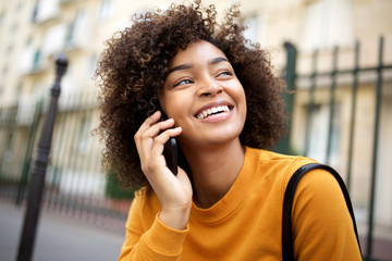 Close up happy african american young woman talking with cellphone outside in city