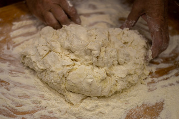 Mix dough by hand on an old wooden board.  Homemade bread making.  Baker’s hands in the process of work close-up