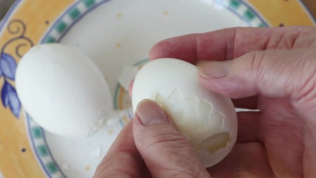 A woman tries to peel a boiled egg
