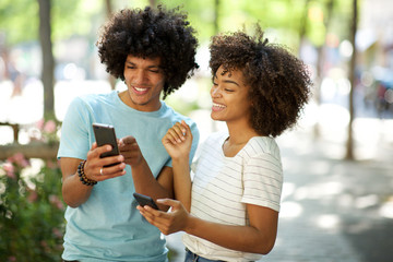 happy afro man showing smiling african american young woman cellphone