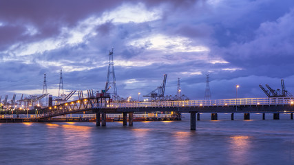 Fototapeta na wymiar Pier in river Scheldt with container terminal on the background, Port of Antwerp, Belgium.