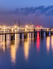 Fototapeta na wymiar Illuminated pier in river Scheldt with container terminal on the background, Port of Antwerp, Belgium.