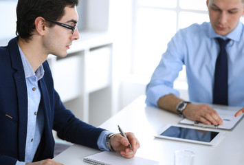 Group of business people discussing questions at meeting in modern office. Managers at negotiation or brainstorm. Teamwork, partnership and business concept