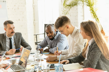 Group of young business professionals having a meeting. Diverse group of coworkers discuss new decisions, future plans and strategy. Creative meeting and workplace, business, finance, teamwork.