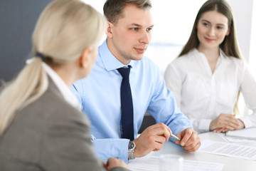 Group of business people discussing questions at meeting in modern office. Managers at negotiation or brainstorm. Teamwork, partnership and business concept