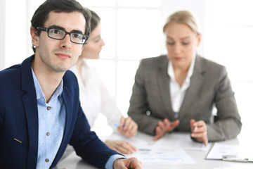 Group of business people discussing questions at meeting in modern office. Headshot of businessman at negotiation. Teamwork, partnership and business concept