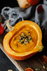 Pumpkin soup in pumpkin. Vegetarian autumn pumpkin cream soup with seeds.