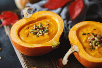 Pumpkin soup in pumpkin. Vegetarian autumn pumpkin cream soup with seeds.