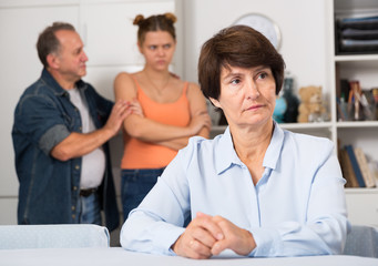 Man and his daughter are sympathying their sad mother who is sitting at the table