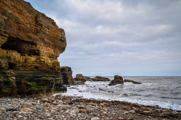 Fototapeta na wymiar Weathered Cliffs and the North Sea, in a cove known as The Wherry, among Magnesian Limestone Cliffs just south of Souter Lighthouse which is full of caves and sea stacks