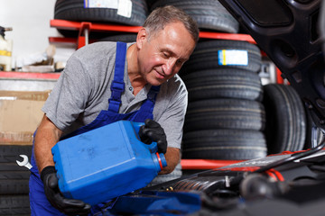 Mechanic checking and replacing motor oil