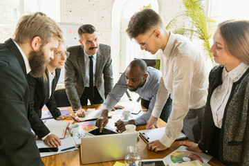 Group of young business professionals having a meeting. Diverse group of coworkers discuss new decisions, future plans and strategy. Creative meeting and workplace, business, finance, teamwork.
